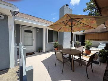 Charming patio area with outdoor seating, perfect for relaxing or entertaining guests under the shade of a large umbrella at 737 Tanglewood Rd, Winter Springs, FL 32708