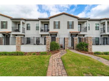 Inviting townhouse exterior with manicured lawn, brick pathway, gated entry, and private balconies at 109 Kenny Blvd, Haines City, FL 33844