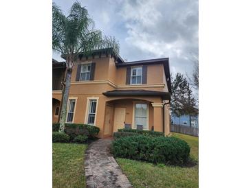 Charming two-story home with a well-manicured lawn and inviting entryway featuring a brick walkway and lush landscaping at 3500 Calabria Ave, Davenport, FL 33897