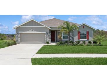 Charming single-story home with a well-manicured lawn, stone accents, and a two-car garage at 6139 Claystone Way, Mount Dora, FL 32757