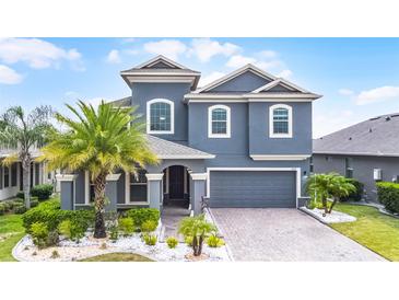 Beautiful two-story home with landscaped yard, blue exterior, and brick driveway at 1003 Nathan Ridge Rd, Clermont, FL 34715