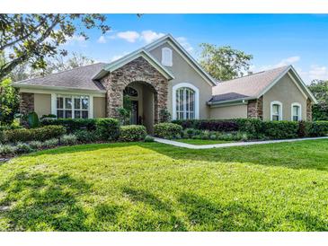 Charming front exterior showcasing well-maintained lawn, stone archway, and beautifully landscaped shrubbery at 162 Seville Chase Dr, Winter Springs, FL 32708