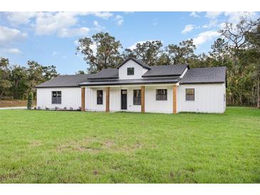 Charming white farmhouse with a metal roof and a large front yard at 12460 Sw 48 Lane Rd, Ocala, FL 34481