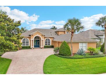 Inviting single-story home featuring a paved driveway, lush landscaping, and a striking arched entryway at 13524 Glynshel Dr, Winter Garden, FL 34787