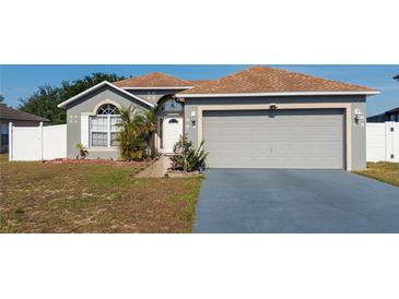 Charming single-story home featuring a well-manicured lawn, arched window, and two-car garage at 212 Ashford Dr, Davenport, FL 33837
