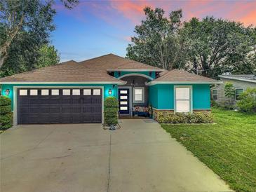 Charming turquoise home featuring a well-kept lawn, a dark grey garage door, and a cozy front porch at 2545 El Portal Ave, Sanford, FL 32773