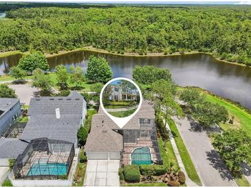 Stunning aerial view of waterfront home with screened-in pool and lush greenery at 3201 Glenmere Way, Orlando, FL 32828