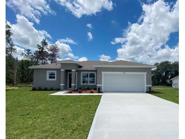 Beautiful single-story home with a well-manicured lawn and a two-car garage on a sunny day at 3498 Sw 131St Place Rd, Ocala, FL 34473