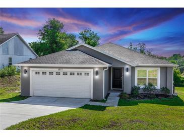 Charming single-story home with gray exterior, well-manicured lawn, and two-car garage at 1857 E Cooper Dr, Deltona, FL 32725
