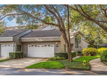 Charming townhome featuring a gray exterior, tile roof, and a two-car garage, complemented by lush landscaping and a tree canopy at 3987 Lancashire Ln # 3987, Longwood, FL 32779