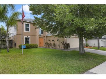 Inviting two-story home with a well-maintained lawn, orange door and lush landscaping at 4927 Fiske Cir, Orlando, FL 32826