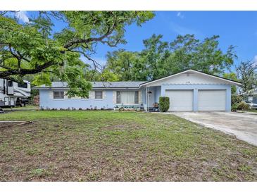 Charming single-story light blue home with an attached two-car garage and mature landscaping in the front yard at 806 Bear Lake Rd, Apopka, FL 32703