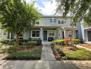Charming two-story townhouse with inviting landscaping, including green shrubs and trees framing the entrance at 8417 Leeland Archer Blvd, Orlando, FL 32836