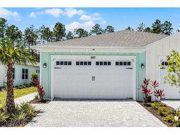 Charming home featuring a spacious white garage door and a beautiful paver driveway at 867 Bama Breeze Dr, Daytona Beach, FL 32124
