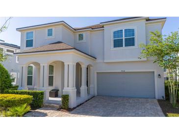 Charming two-story home featuring an inviting front porch with columns and a paved driveway to a two-car garage at 9038 Sunshine Ridge Loop, Kissimmee, FL 34747