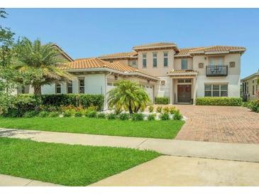 Inviting two-story home featuring lush landscaping, a terracotta tile roof, and a brick paved driveway at 13125 Alderley Dr, Orlando, FL 32832