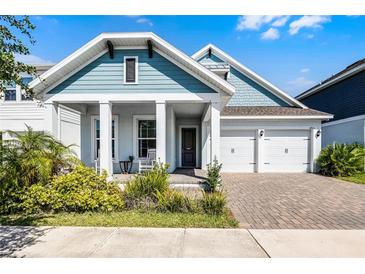 Charming two-story home with blue accents, a welcoming front porch, and a brick driveway leading to a two-car garage at 14925 Lebeau Loop, Winter Garden, FL 34787