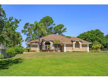 Beautiful one-story home featuring a well-manicured lawn, lush landscaping, and a neutral-colored exterior at 513 N Pine Meadow Dr, Debary, FL 32713