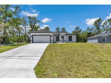 A charming single-story home boasting a well-manicured lawn and a modern white exterior with black trim at 6691 Sw 151Sr Loop, Ocala, FL 34473