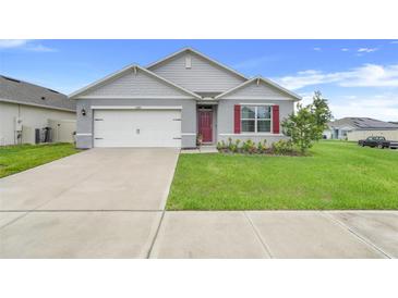 Charming single-story home with a well-maintained lawn and a two-car garage at 11284 Amber Ridge Dr, Zellwood, FL 32798