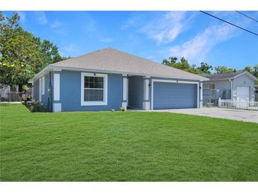 Charming single-story home featuring blue siding, a well-manicured lawn, and an attached two-car garage at 1621 Sunny St, Kissimmee, FL 34741