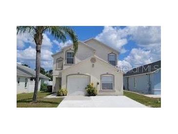 Two-story home with stucco siding, a palm tree, and a well-maintained lawn on a bright day at 2524 Hamlet Ln, Kissimmee, FL 34746