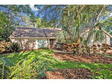 Charming brick home featuring a well-manicured lawn, mature trees, and beautiful landscaping at 828 Timber Court Ct, Apopka, FL 32712