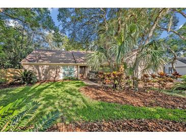 Charming brick home featuring a well-manicured lawn and lush tropical landscaping at 828 Timber Court Ct, Apopka, FL 32712