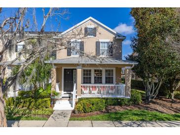 Charming two-story home featuring a cozy front porch with white railings and lush landscaping at 9141 Camden Gardens St, Orlando, FL 32827