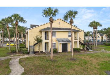 Inviting yellow two-story building with tropical landscaping and classic exterior stairway at 1031 S Hiawassee Rd # 2517, Orlando, FL 32835