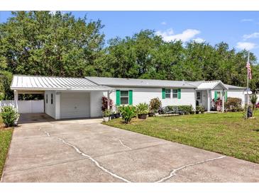Charming single-story home featuring a driveway, metal roof and well-maintained lawn at 13009 Plum Lake Cir, Minneola, FL 34715