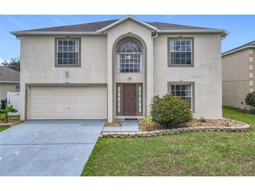 Two-story home showcasing a manicured lawn, neutral stucco, and a spacious two-car garage at 2384 Andrews Valley Dr, Kissimmee, FL 34758