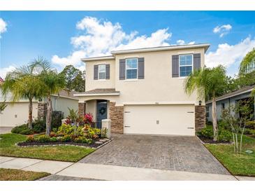 Charming two-story home featuring a stone facade, manicured landscaping, and a brick-paved driveway at 266 Caryota Ct, New Smyrna Beach, FL 32168