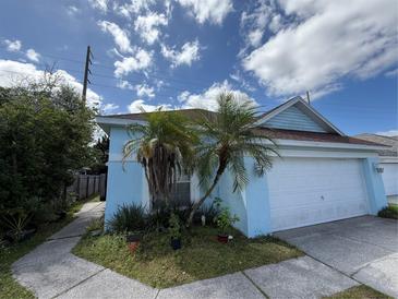 Charming light blue home featuring a white garage door and complemented by palm trees in the front yard at 307 Hollingshead Loop, Davenport, FL 33896