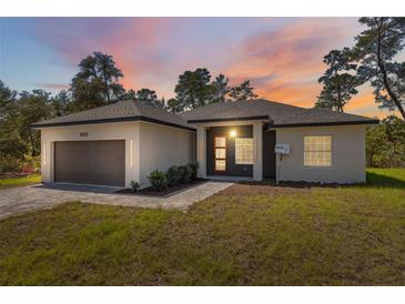 Inviting single-story home featuring a two car garage, modern design, and well-maintained landscaping at sunset at 3072 Sw 168Th Loop, Ocala, FL 34473