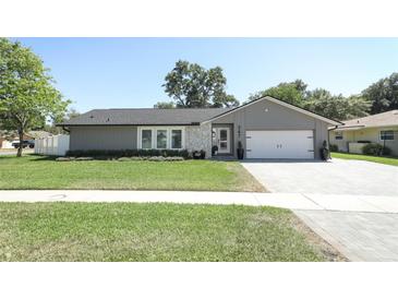 Charming single-story home with a well-manicured lawn and a gray exterior with stone accents at 347 Timberwood Trl, Oviedo, FL 32765