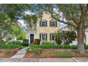 Charming two-story home featuring a balcony, black shutters, lush landscaping, and mature trees in a desirable neighborhood at 4001 Corrine Dr, Orlando, FL 32814