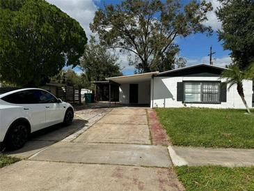 Charming single-story home with a long driveway and a modern white car parked in front at 4061 Kirkland Blvd, Orlando, FL 32811