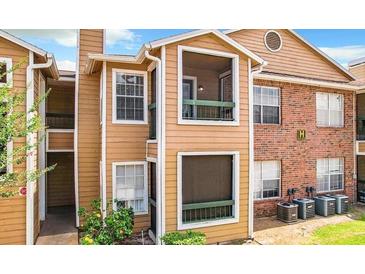 View of the exterior elevation of the building with a combination of wood and brick, and a few windows at 5540 Devonbriar Way # 103, Orlando, FL 32822