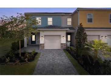 Charming two-story townhome with a well-manicured front yard and a paved driveway leading to an attached garage at 772 Driving Range Ct, Kissimmee, FL 34747