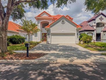 Charming two-story home featuring a red tile roof, a brick driveway and lush landscaping at 8515 Saint Marino Blvd, Orlando, FL 32836