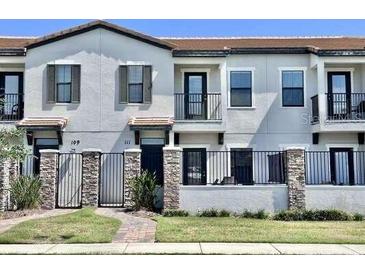 Modern townhome exterior with neutral paint, black iron gates, and well maintained front lawn and professional landscaping at 123 Kenny Blvd, Haines City, FL 33844