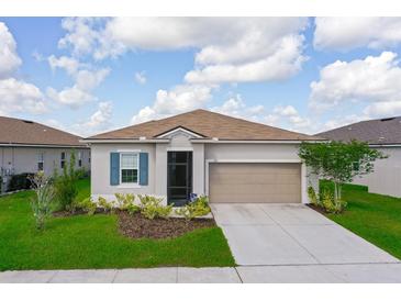 Charming single-story home featuring a well-manicured lawn, a two car garage, and beautiful landscaping at 200 Summershore Dr, Auburndale, FL 33823