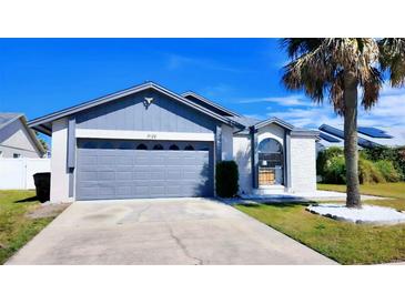 Charming single-Gathering home featuring a gray two-car garage and a well-manicured lawn at 3129 Arrow Dr, Kissimmee, FL 34746