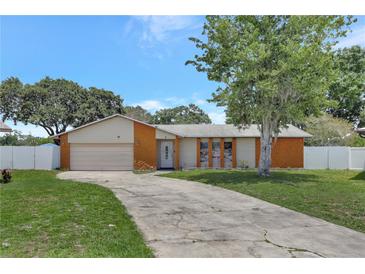 Charming single-story home featuring an attached garage and spacious front yard with mature tree, and long driveway at 7 Madeira Ave, Orlando, FL 32825