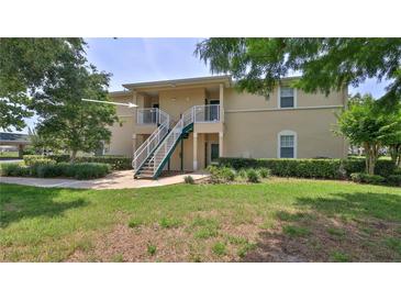 Inviting two-story condo with lush landscaping and stairs leading to the second level at 830 Airport Rd # 115, Port Orange, FL 32128