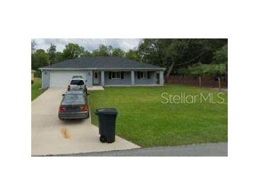 Charming single-story home with a columned front porch and a well-manicured front lawn at 9338 Se 157Th Pl, Summerfield, FL 34491
