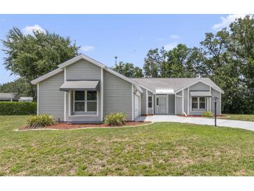 Charming single-story home featuring a well-maintained lawn and neutral-toned siding at 1243 Tangerine Cir, Lady Lake, FL 32159