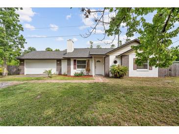 Charming single-Gathering home featuring a brick and white exterior, well-maintained lawn, and attached garage at 2040 E Triangle Dr, Longwood, FL 32779
