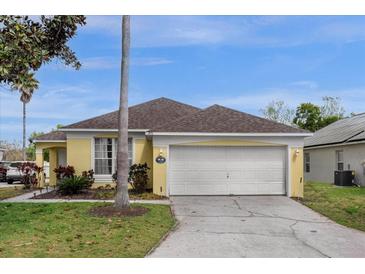 Charming yellow home featuring a two-car garage, well-maintained lawn, and inviting curb appeal at 217 Holborn Loop, Davenport, FL 33897